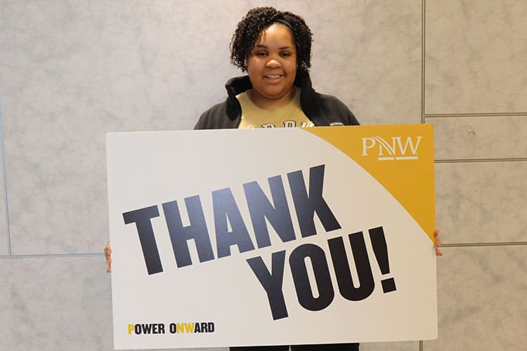 Tamar Clark holds a PNW branded "Thank You!" sign
