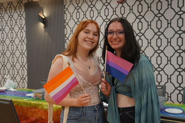 Two students pose together with pride flag
