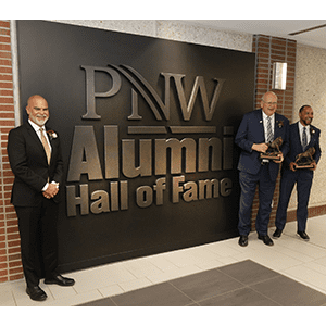 PNW 2023 Alumni Hall of Inductees Alfredo “Al” Sori, Stewart “Stu” McMillan and Robert Johnson III in front of the Alumni Hall of Fame Display in the Student Union and Library Building