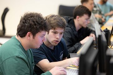 Two PNW students work at computers during a class.